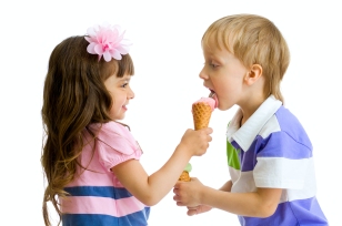 girl shares, gives or feeds boy with her ice cream in studio iso